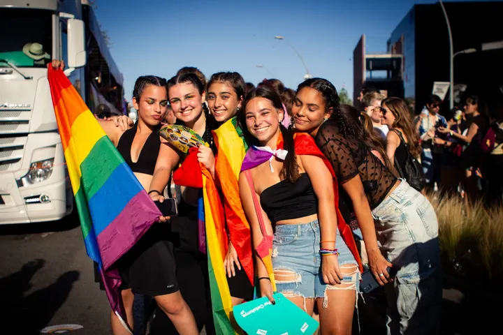 Grupo de mujeres sonrientes con banderas arcoíris celebra el Orgullo en la calle