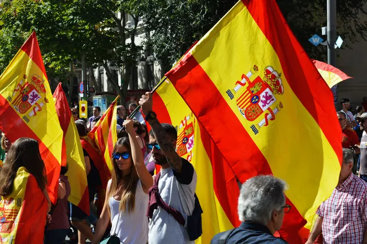 Un grupo de personas, probablemente en Madrid, con banderas de España, celebrando o manifestando