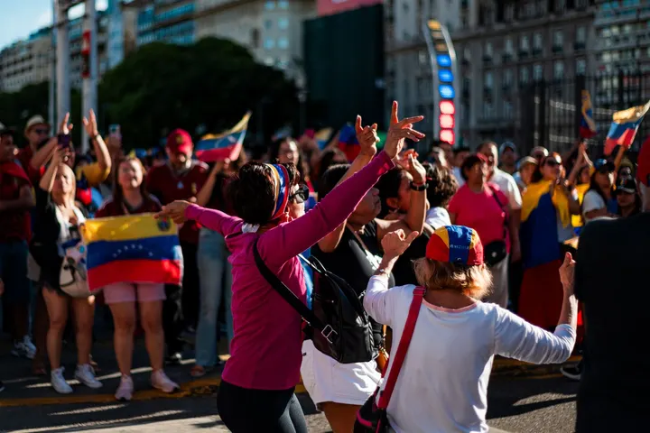 Un grupo de mujeres con banderas de Venezuela, en una calle