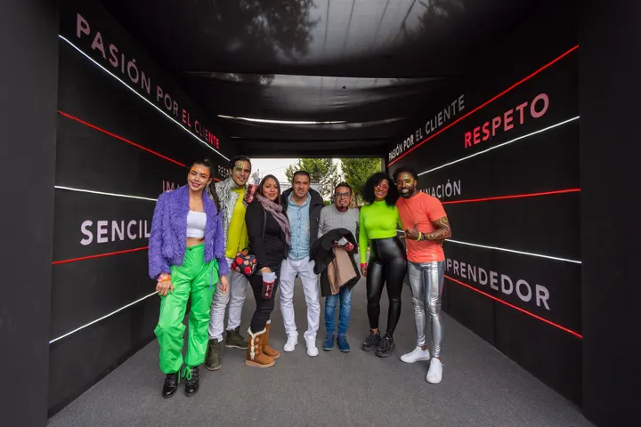 Un grupo de ocho personas, en un pasillo con una pared con palabras en español, posan para una foto