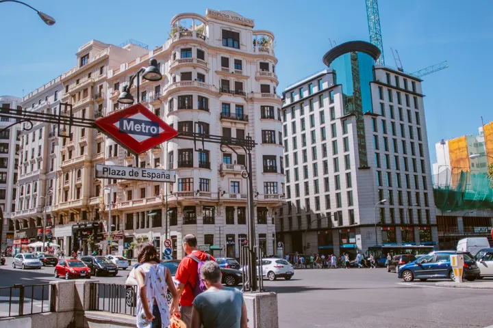 Un hombre y una mujer caminan por la calle Plaza de España, en Madrid, España, mirando hacia el metro