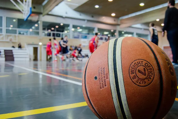 Un balón de baloncesto, un grupo de personas jugando en un gimnasio