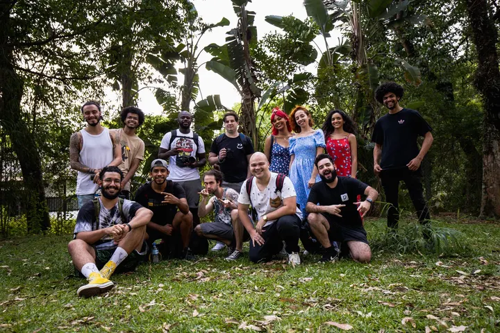 Un grupo de personas, posando para una foto, en un jardín con árboles y hierba